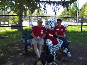 Chris and Karry Borolo, founders of D.O.G. Bakery, sitting on bench at dog park with their 'human' dog Bisquit