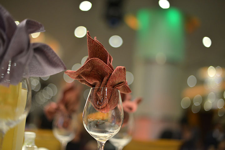 Wineglass with a napkin in the top as part of a place setting.
