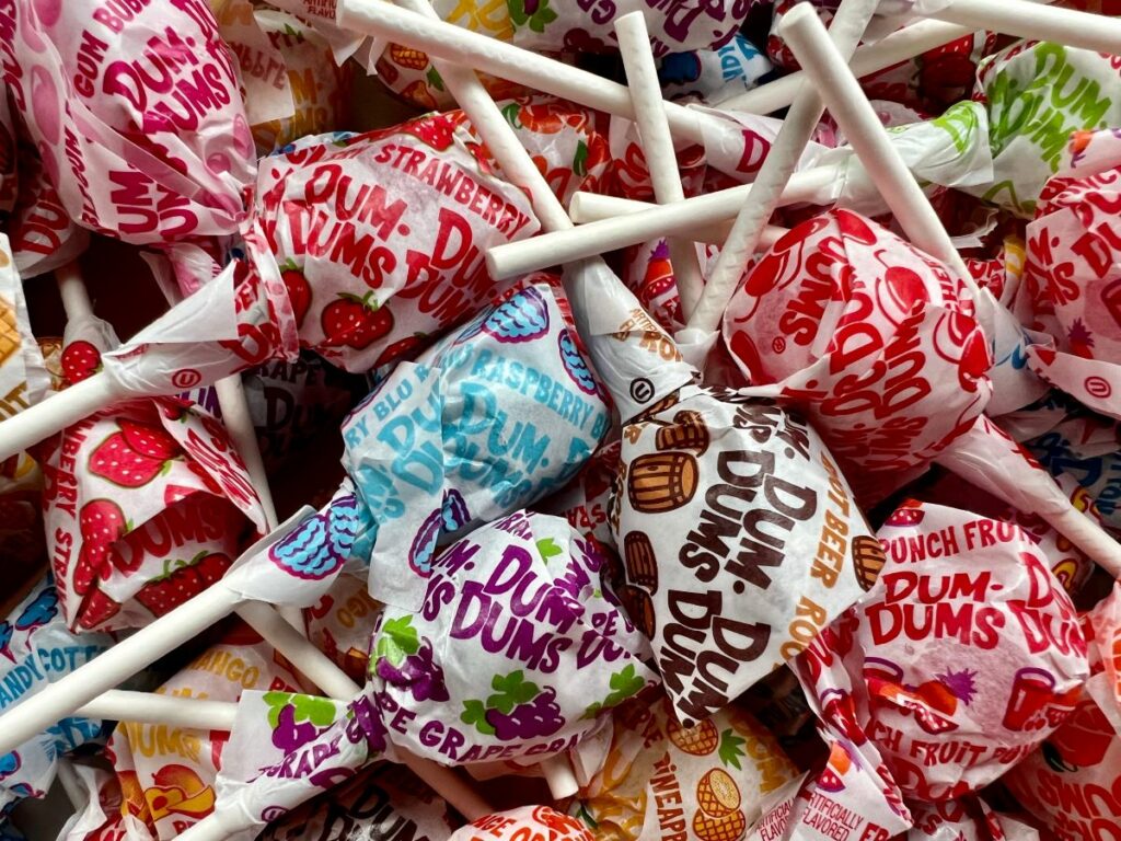 Closeup of a pile of Dum Dums lollipops in various flavors.