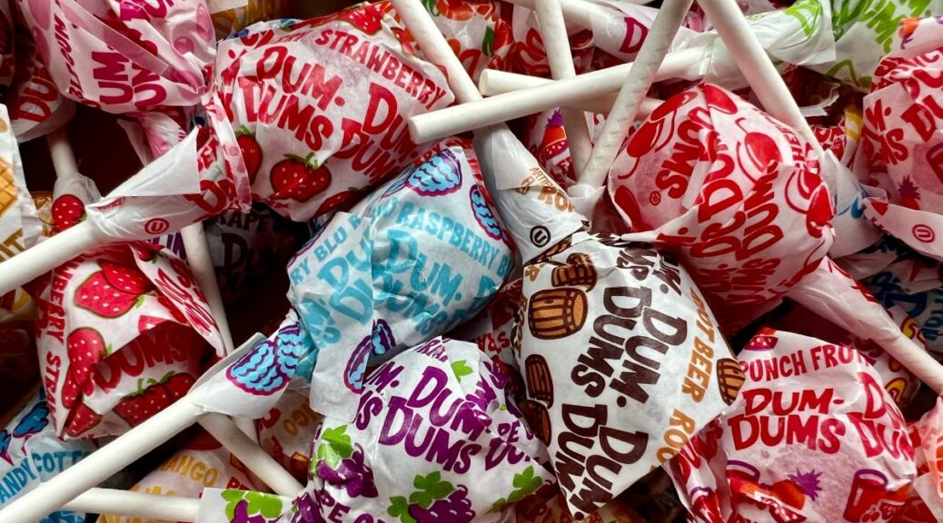 Closeup of a pile of Dum Dums lollipops in various flavors.