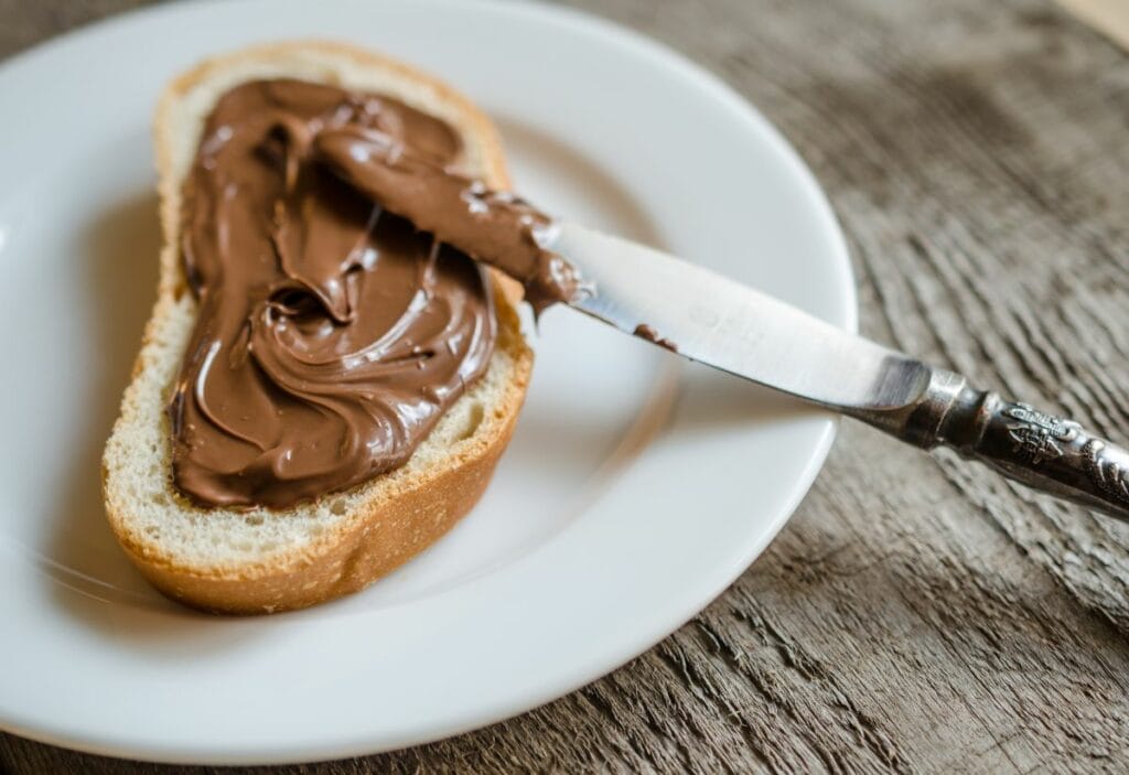 Nutella spread on bread next to a knife.