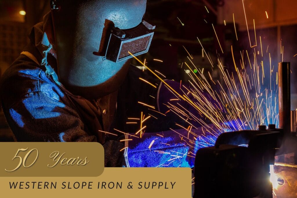 a metalworker wearing a mask welding. Sparks are shooting from the metal.